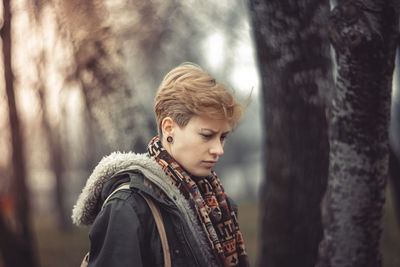 Close-up of thoughtful woman standing by tree in forest