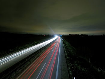 Light trails on road against sky at night