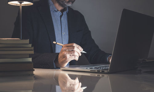 Midsection of woman using laptop while sitting on table