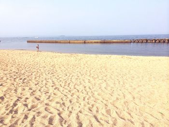 Woman standing on shore at beach against sky