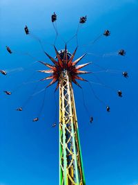 Low angle view of chain swing ride against clear blue sky