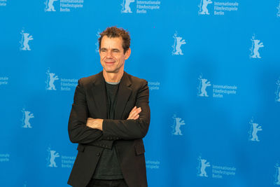 Portrait of smiling man standing against blue wall