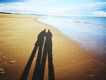 Shadow of people on beach against sky