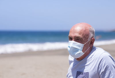 Senior man with mask on shore at beach