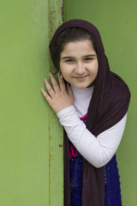 Portrait of smiling young woman standing against wall