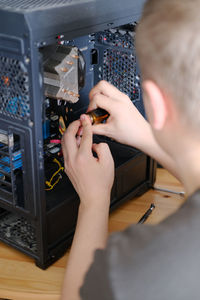 A man disassembles a computer system unit with a screwdriver