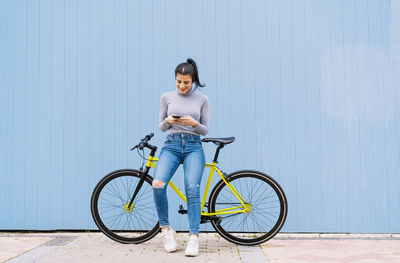 Full length of woman riding bicycle against wall