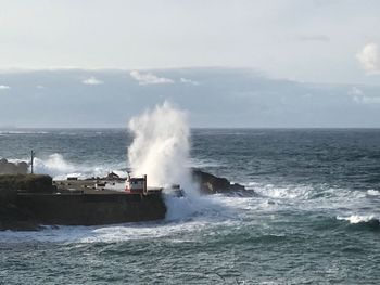 Scenic view of waves splashing on sea against sky