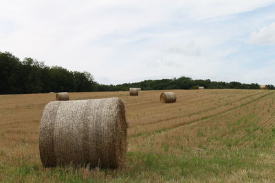 Hay bales on field against sky