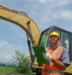 Man working with yellow umbrella against sky