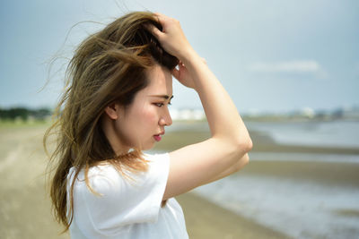 Portrait of woman standing at beach against sky