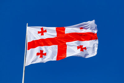 Low angle view of flag against blue sky