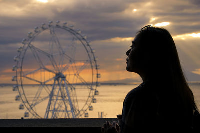 Close-up of young woman against sky at sunset