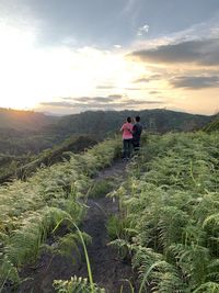 Rear view of people on landscape against sky during sunset