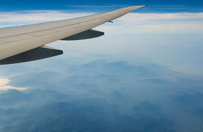 Wing of plane over mountain. airplane flying on blue sky and white clouds. scenic view.