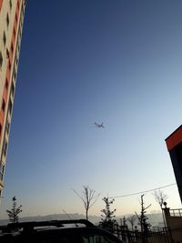 Low angle view of airplane flying against clear blue sky