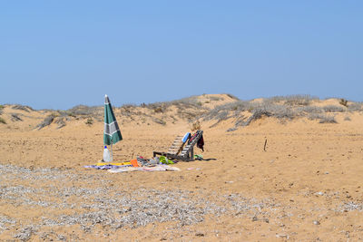 People on sand dune against clear sky