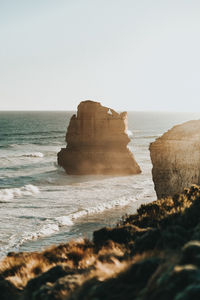 Scenic view of rocks in sea against clear sky