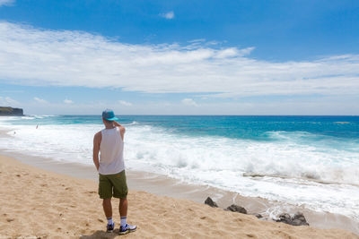 Rear view of man standing at beach against sky