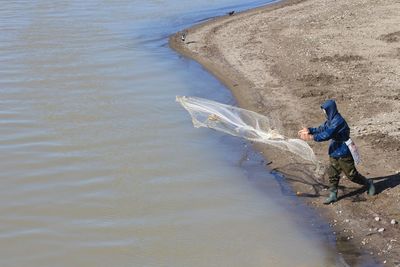 Man throwing fishing net in sea