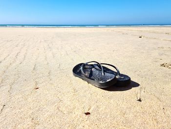 High angle view of shoes on sand at beach against sky