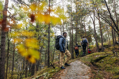 Side view of smiling man standing on trail in forest