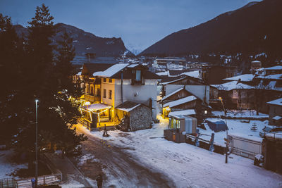 Houses by snow covered mountains against sky