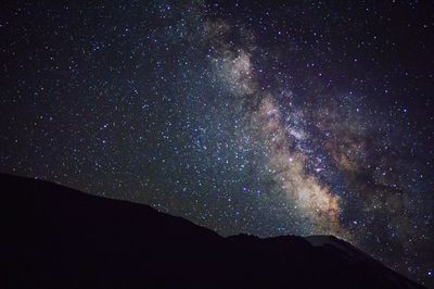 Low angle view of silhouette mountain against star field