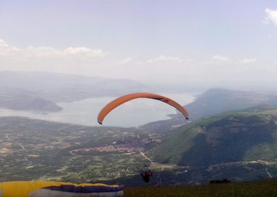 Person paragliding over mountains against sky