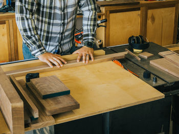 A woodworker cutting pieces of wood for the box he is working on, on the table saw