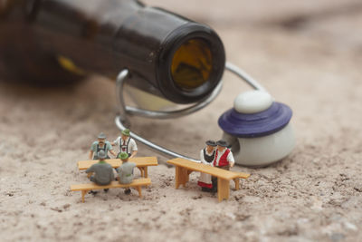 Close-up of figurines and bottle on sand