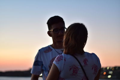 Young couple kissing against sky during sunset