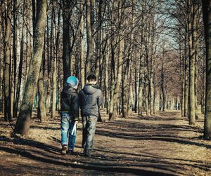 Rear view of people walking in forest