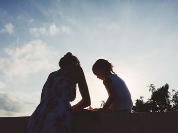 Low angle view of mother and daughter against sky