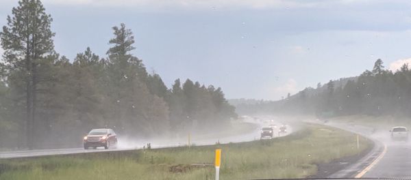 Cars on road against sky during rainy season