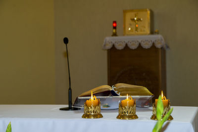 Close-up of the candles and a book on the church table near altar