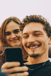 Smiling man showing mobile phone to friend on terrace at rooftop party