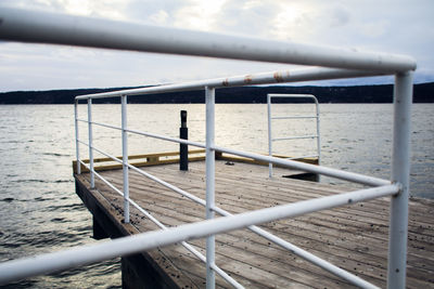 Metal railing by sea against sky