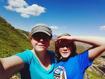 Portrait of smiling mother and daughter wearing sunglasses on mountain