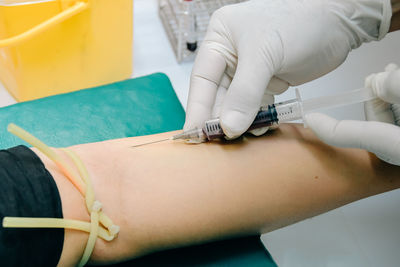 Cropped hands injecting patient in hospital