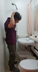 Side view of man standing in bathroom