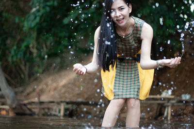 Portrait of cheerful woman splashing water in lake