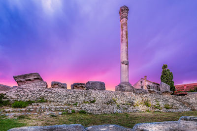 Lighthouse by sea against sky during sunset