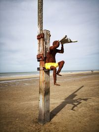 Man jumping at beach against sky