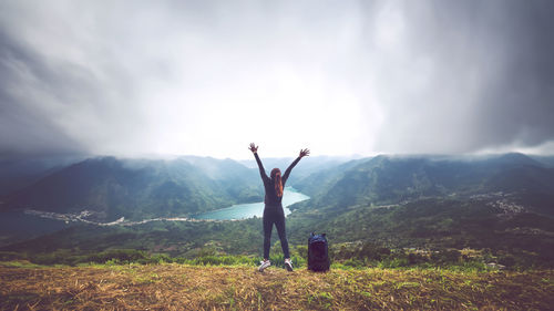 Rear view of man standing on mountain against sky