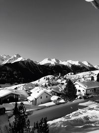 Snow covered houses and mountains against sky