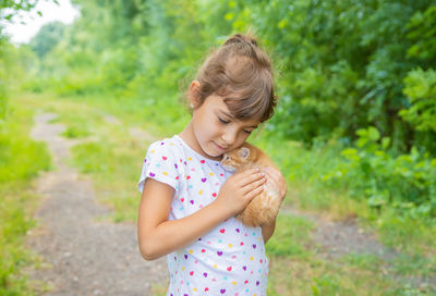 Girl holding kitten on dirt road