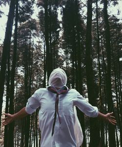 Man with face covered while standing in forest