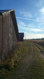 Barn on grassy field against blue sky