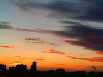 Silhouette buildings against dramatic sky during sunset